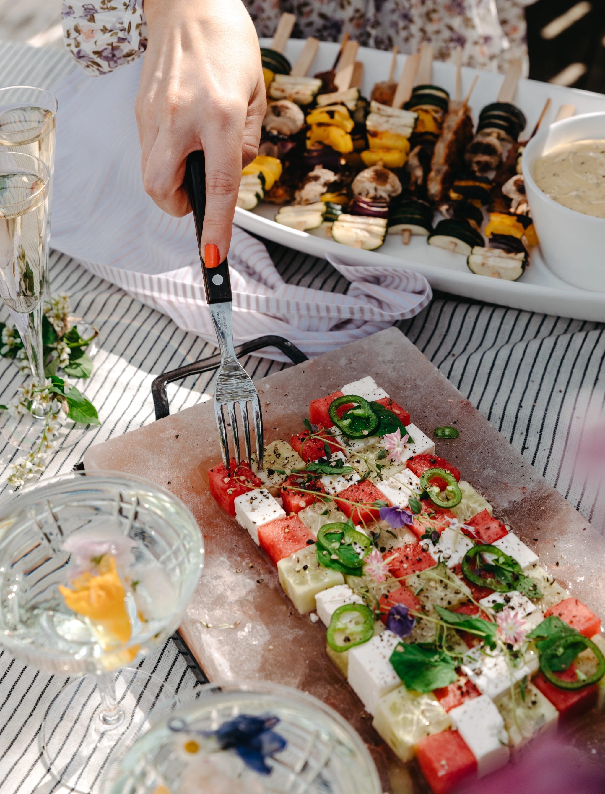 Grillspett och sallad med melon och fetaost på ett somrigt bord