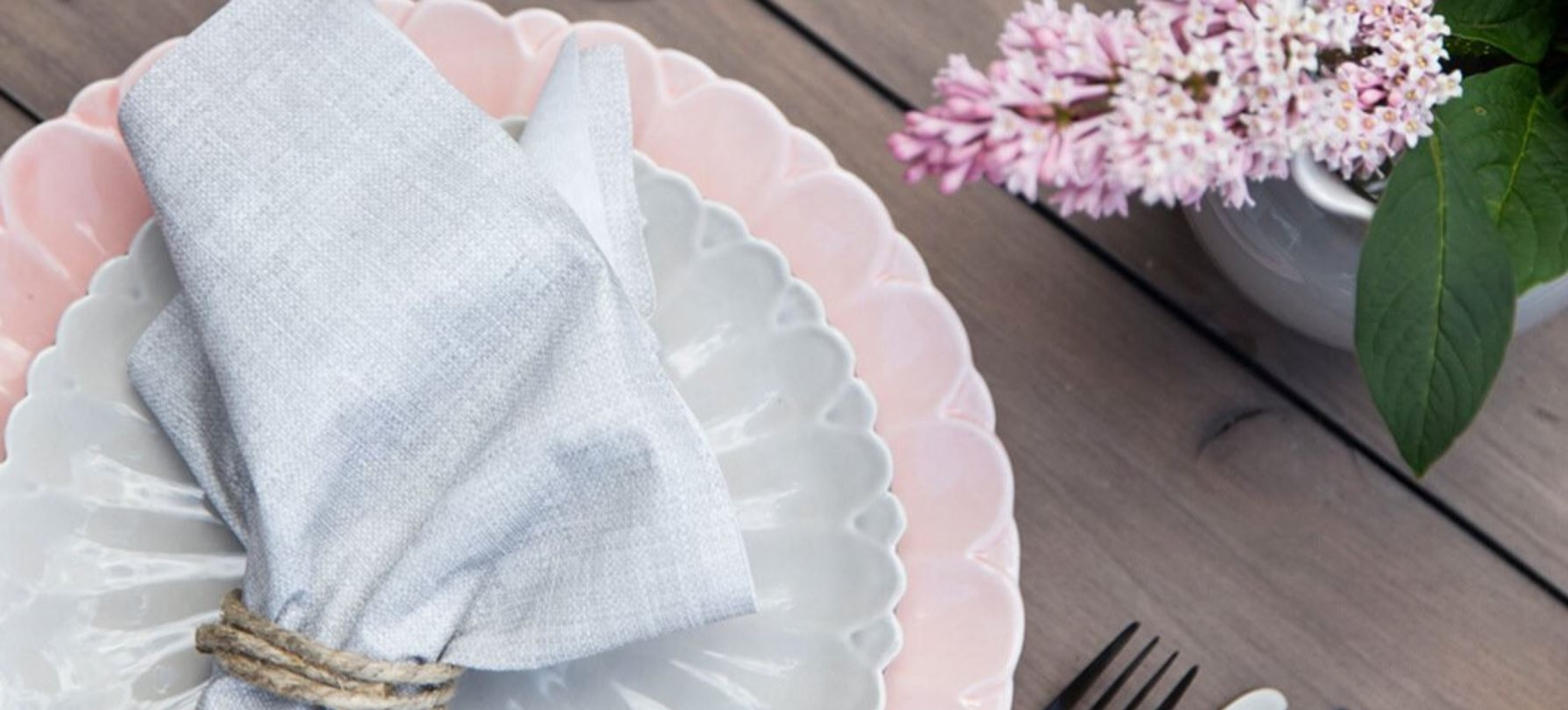 Gerbera tallerkener i hvitt og pastellrosa dekket på et trebord