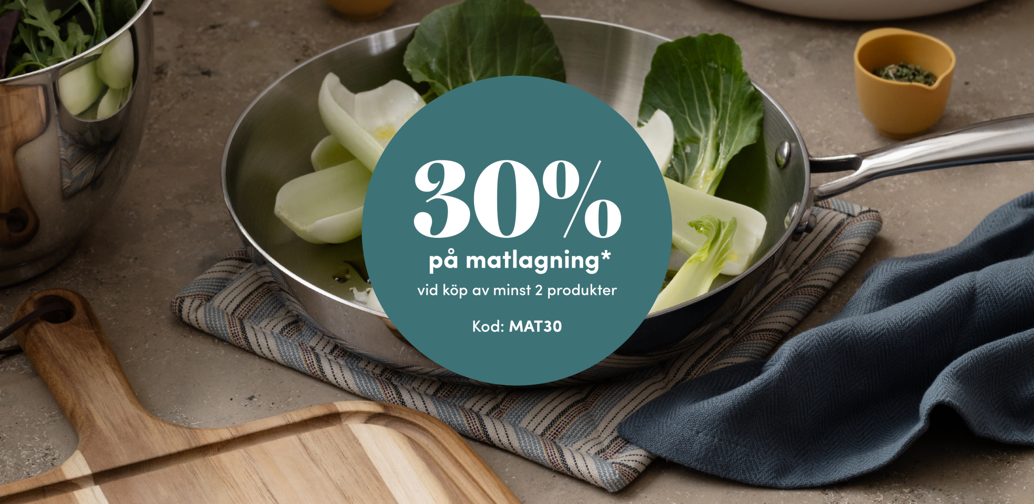 En stekpanna med pak choi och en petrolblå cirkel där det står "30% på matlagning vid köp av minst 2 produkter". Ange kod MAT30