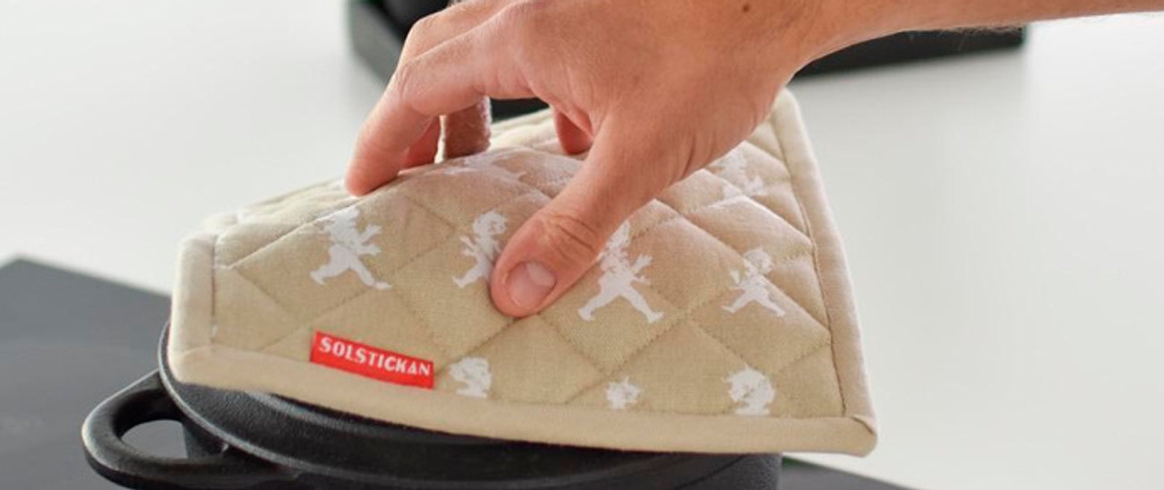 a person is putting an oven mitt on top of a pot .