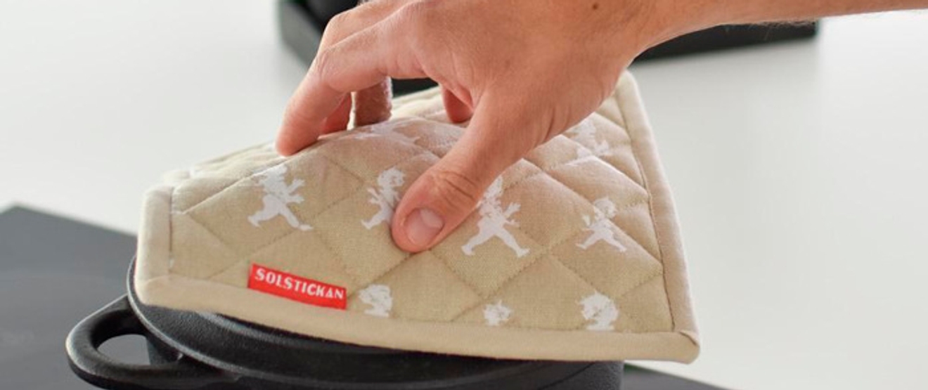 Henkilö asettaa patakintaan kattilan päälle.