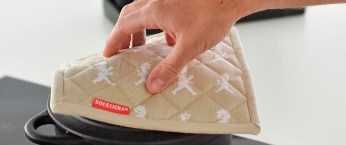 Henkilö asettaa patakintaan kattilan päälle.