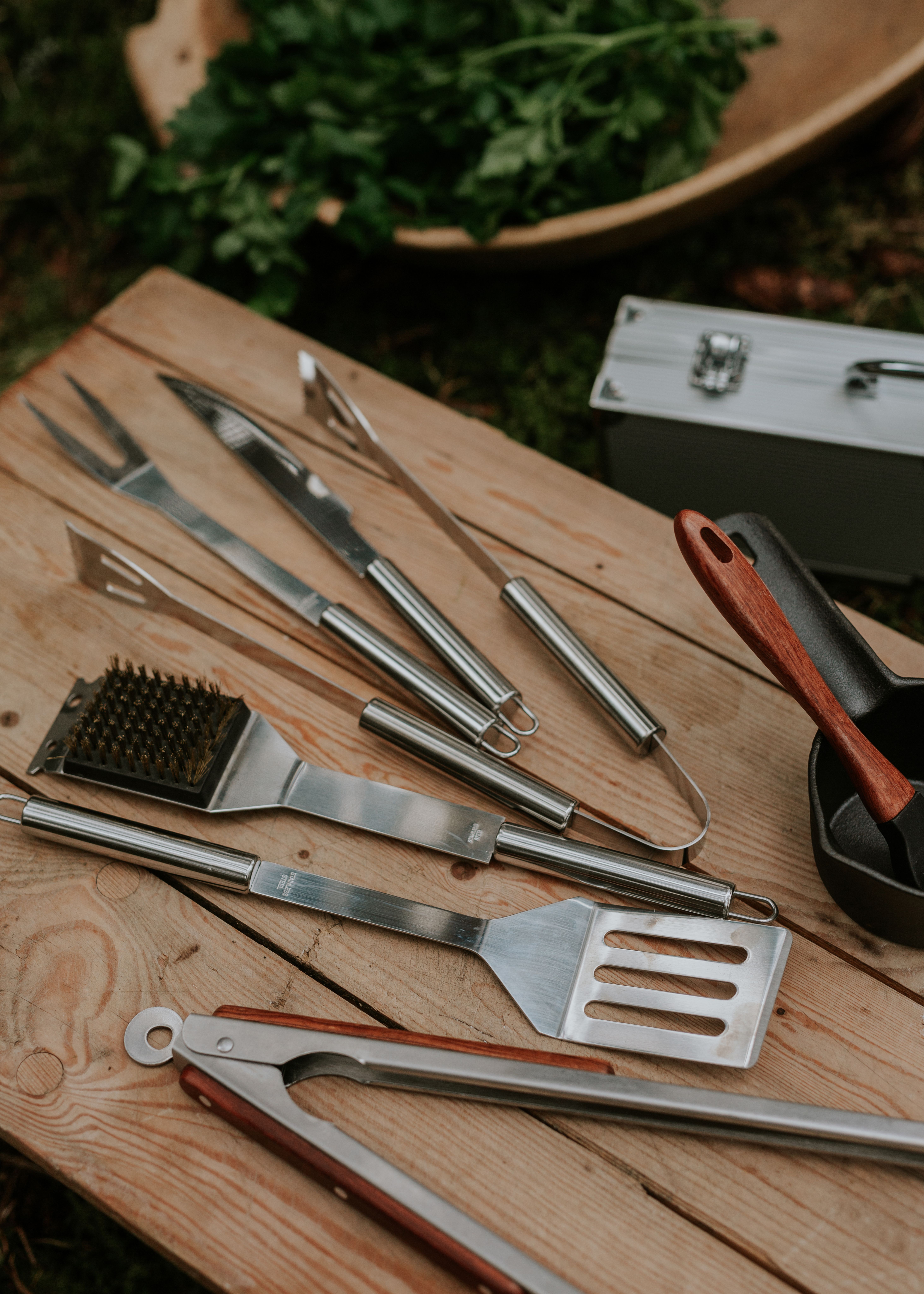 Närbild av grillverktyg i rostfritt stål på en träyta.