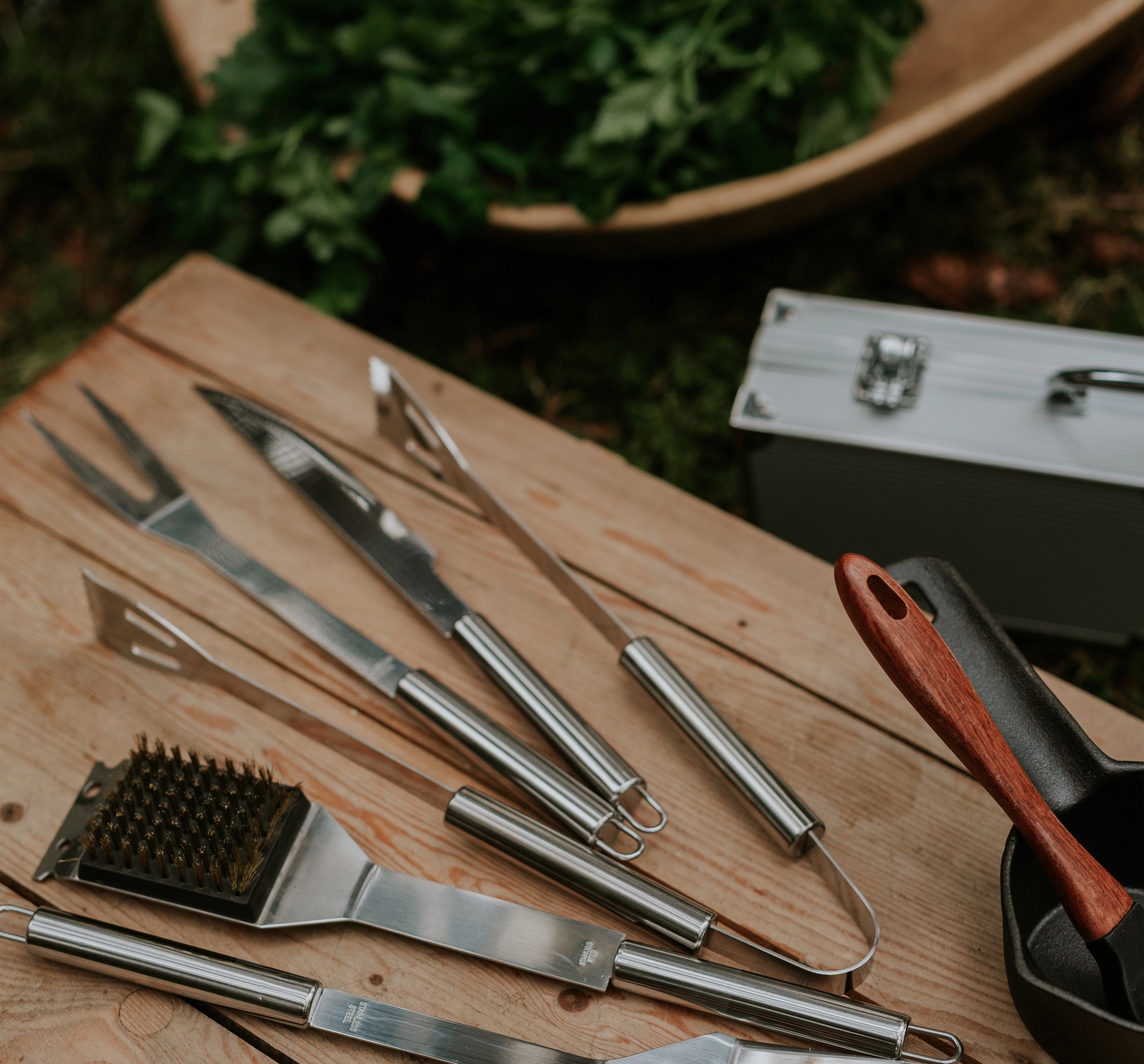 Närbild av grillverktyg i rostfritt stål på en träyta.