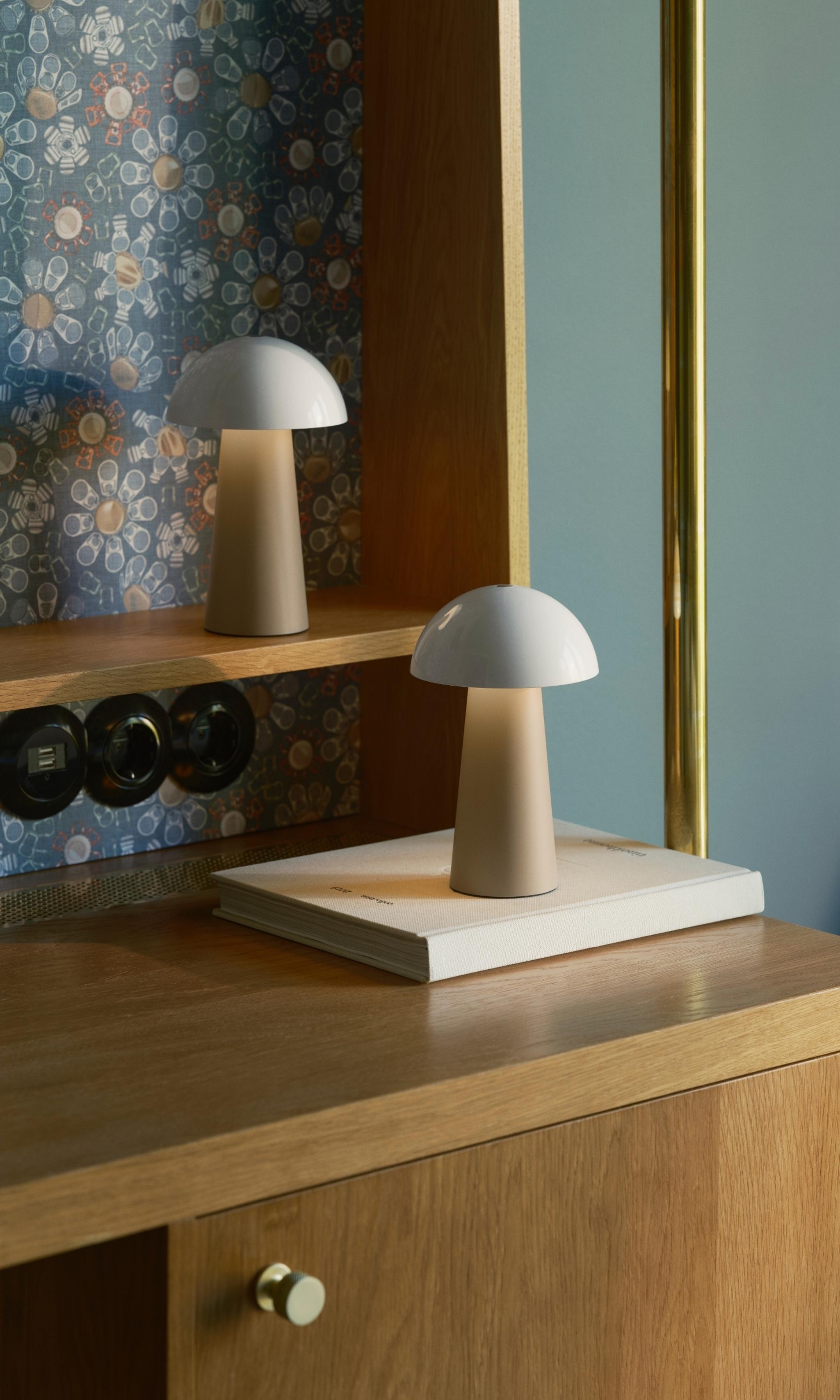 Två moderna svampformade lampor på ett träskrivbord mot mönstrad tapet.