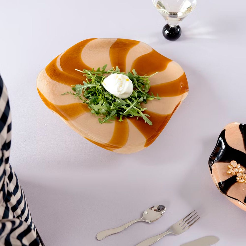 Tyylikkäällä aaltomaisella lautasella tarjoiltu rucolasalaatti ja burrata-juusto kattauksessa.