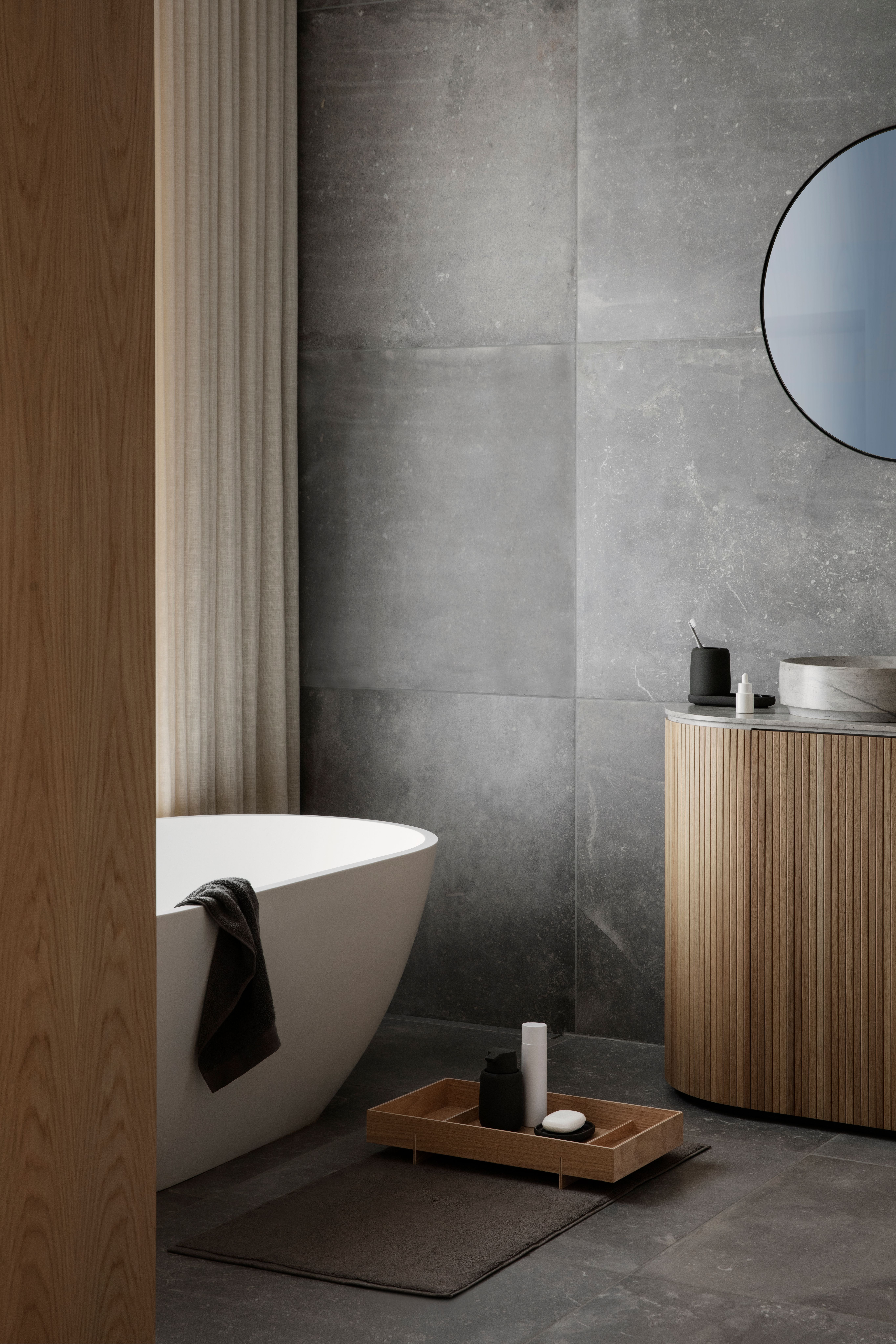 Vitt badkar i ett kaklat badrum i sten med trädetaljer