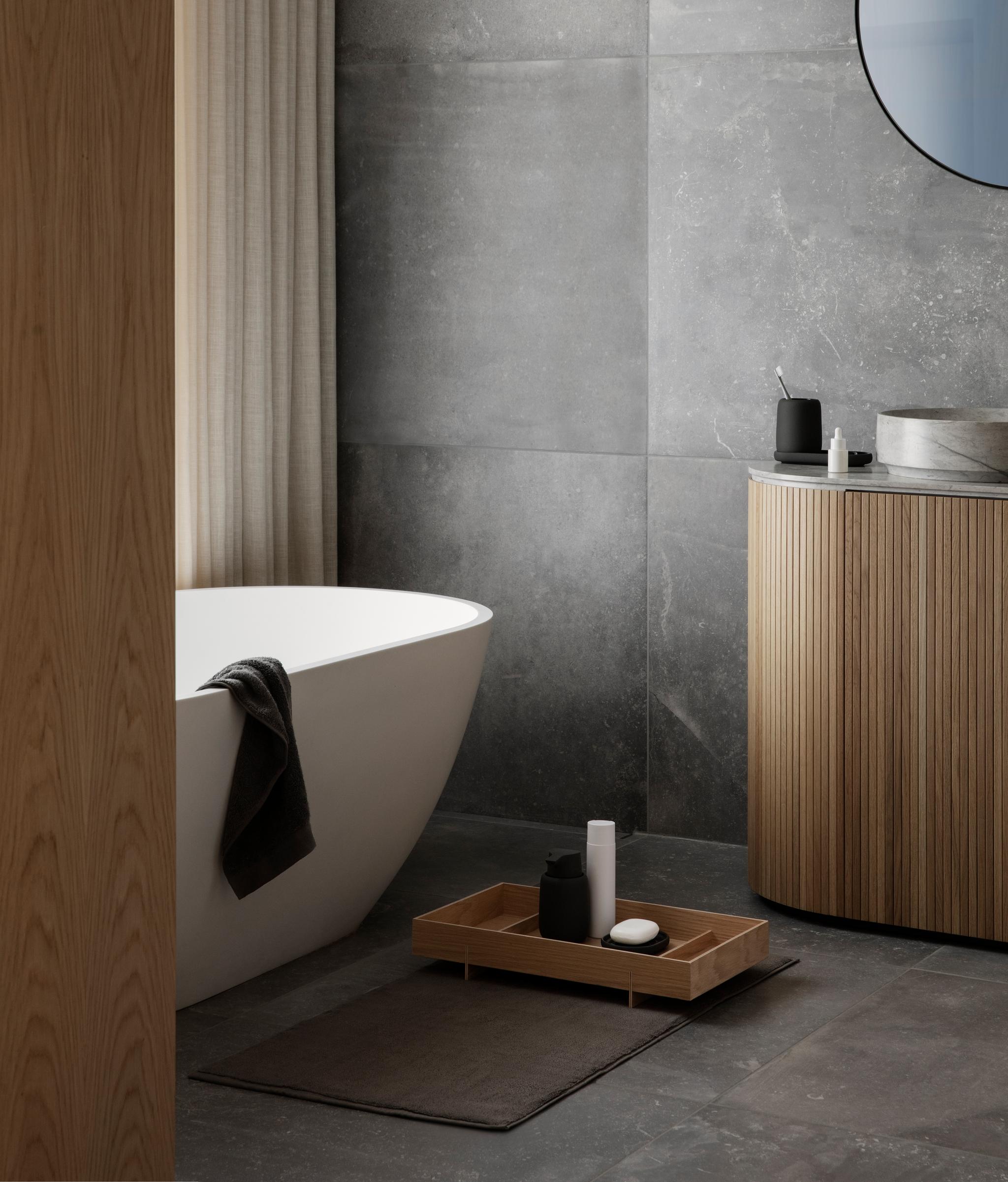 Vitt badkar i ett kaklat badrum i sten med trädetaljer