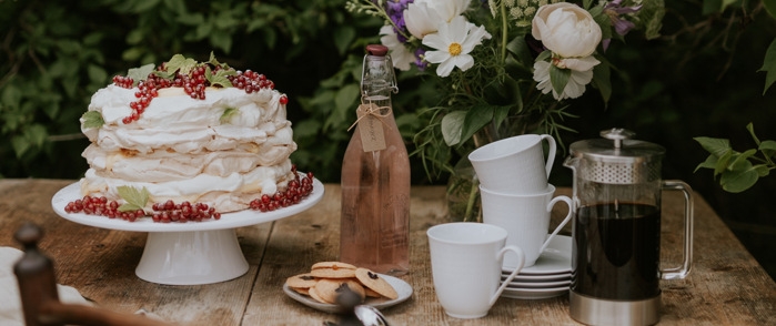 Kakfat & Tårtfat, marängtårta med grädde och röda vinbär samt småkakor och kaffe bredvid