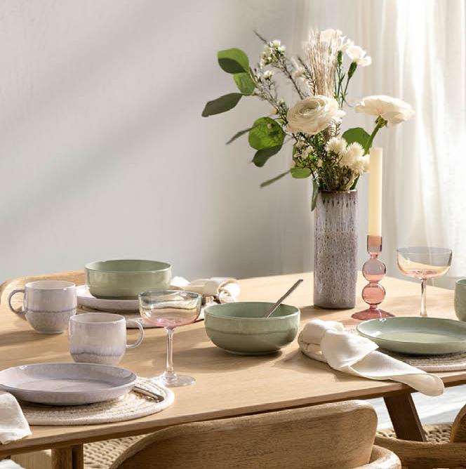 ett matbord med tallrikar, skålar, glas och en vas med blommor på det.