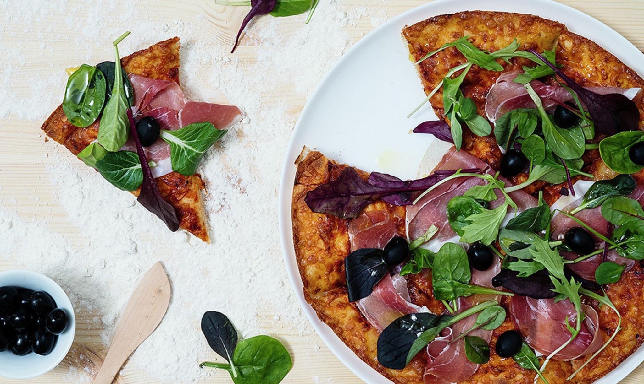 Pizzatallrikar med pizza på mjöligt träbord 