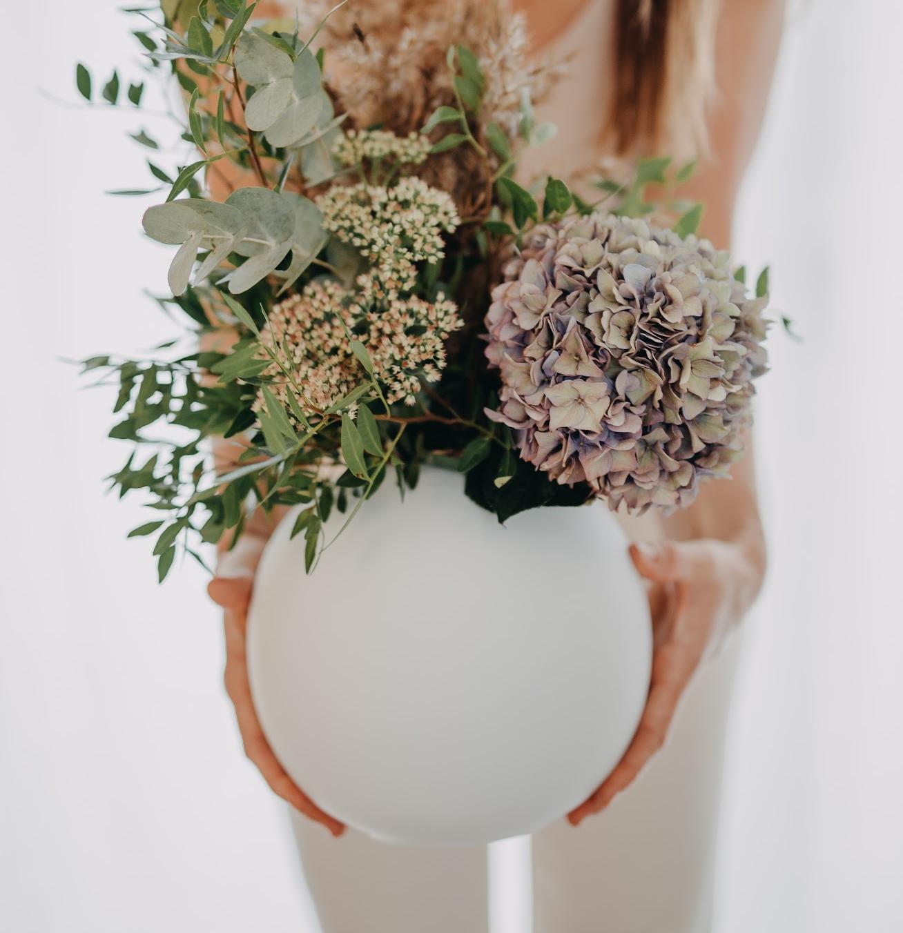 valkoinen pyöreä maljakko kukkakimpun kera