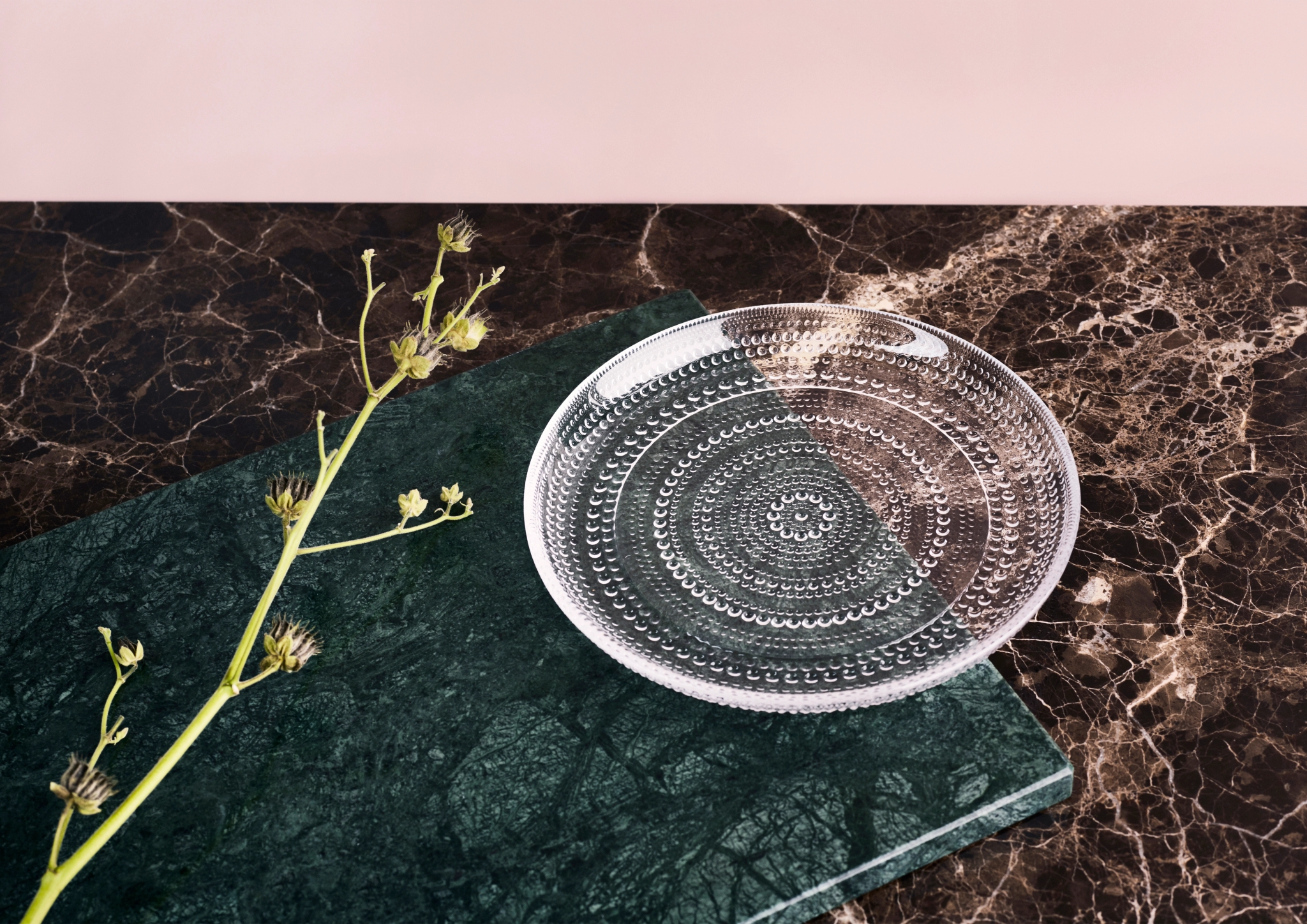 Glasstallerken i gjennomsiktig glass på en mørk marmor bordplate