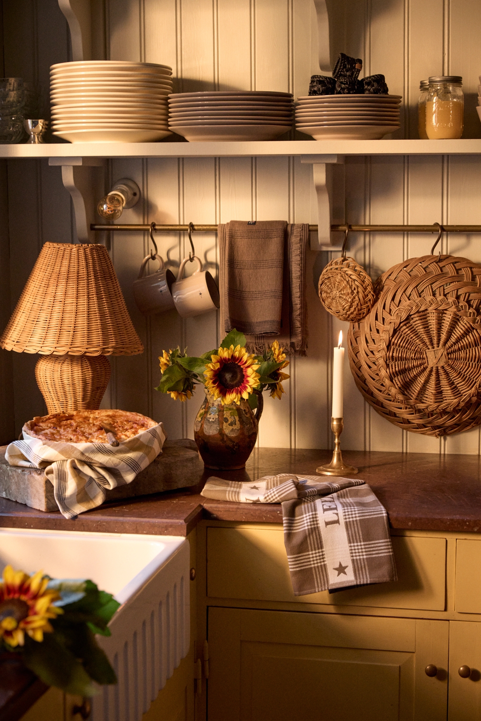 a kitchen counter with a pie and a wicker lamp
