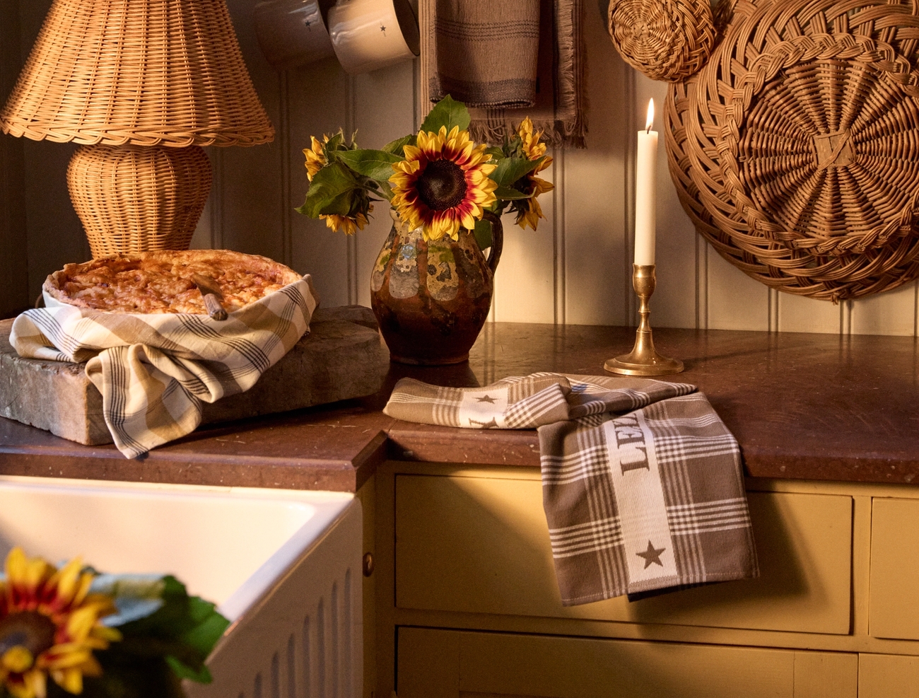 a kitchen counter with a pie and a wicker lamp