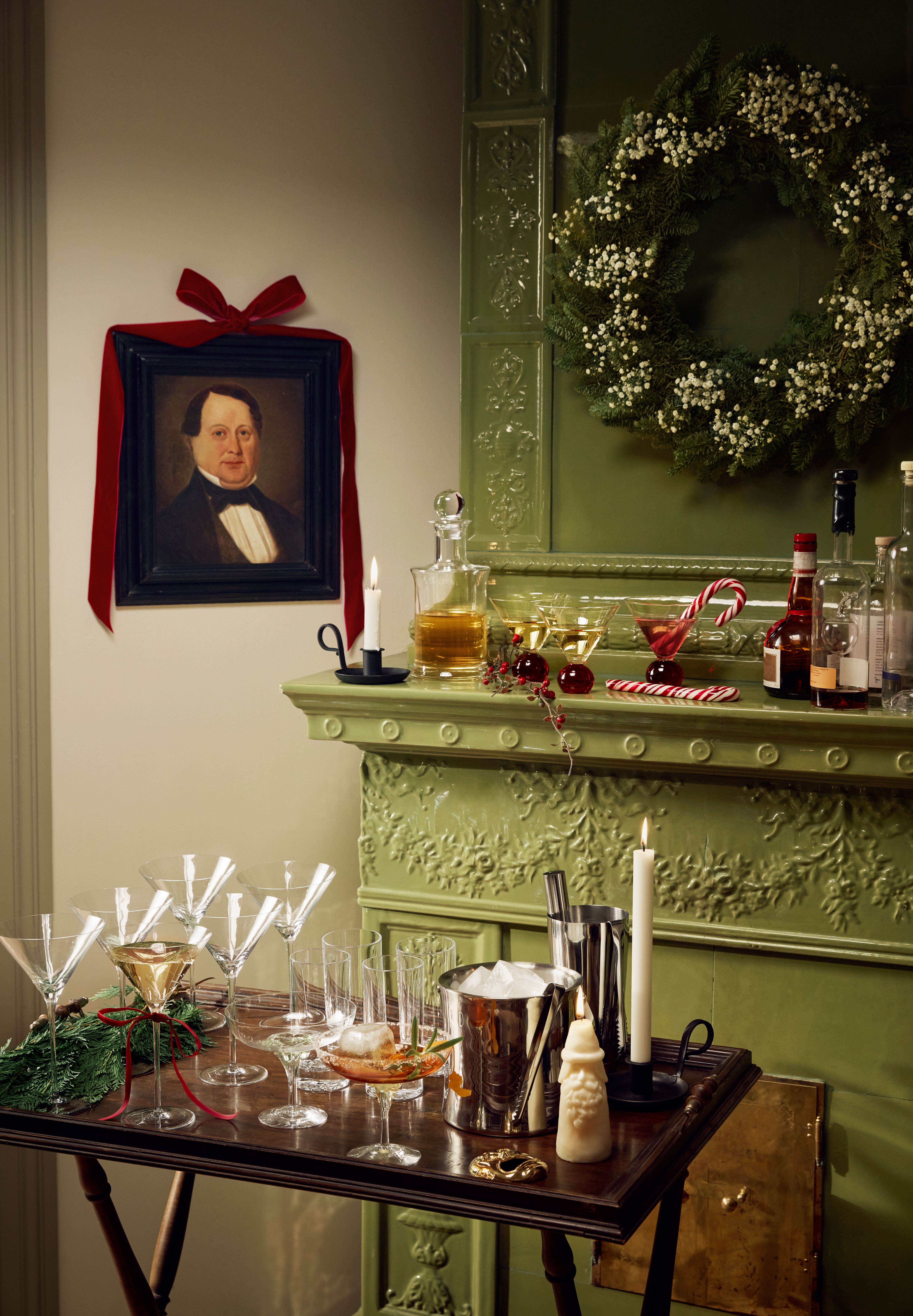 En drikkevogn med martiniglass, isbøtte og shaker står foran en grønn peis