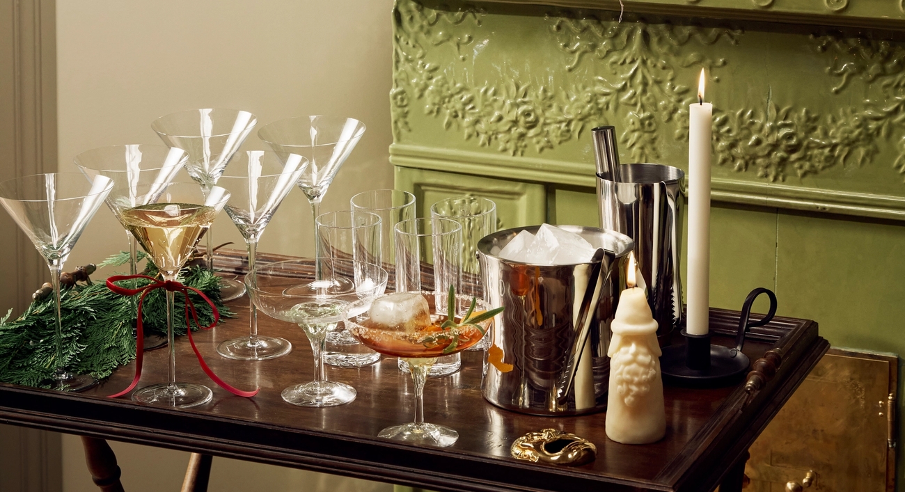 Juomakärry martinilaseineen, jääämpäri ja ravistin seisoo vihreän takan edessä