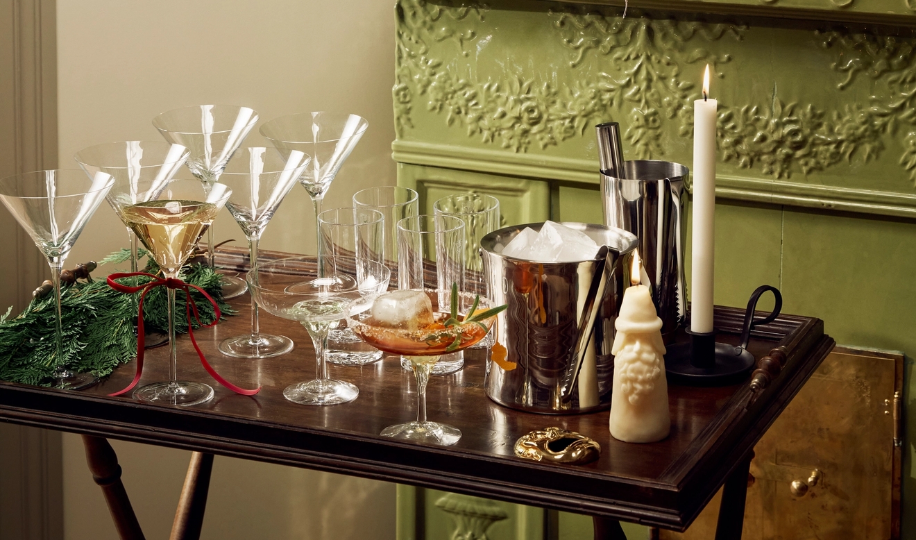 En drikkevogn med martiniglass, isbøtte og shaker står foran en grønn peis