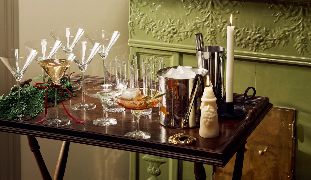 En drikkevogn med martiniglass, isbøtte og shaker står foran en grønn peis