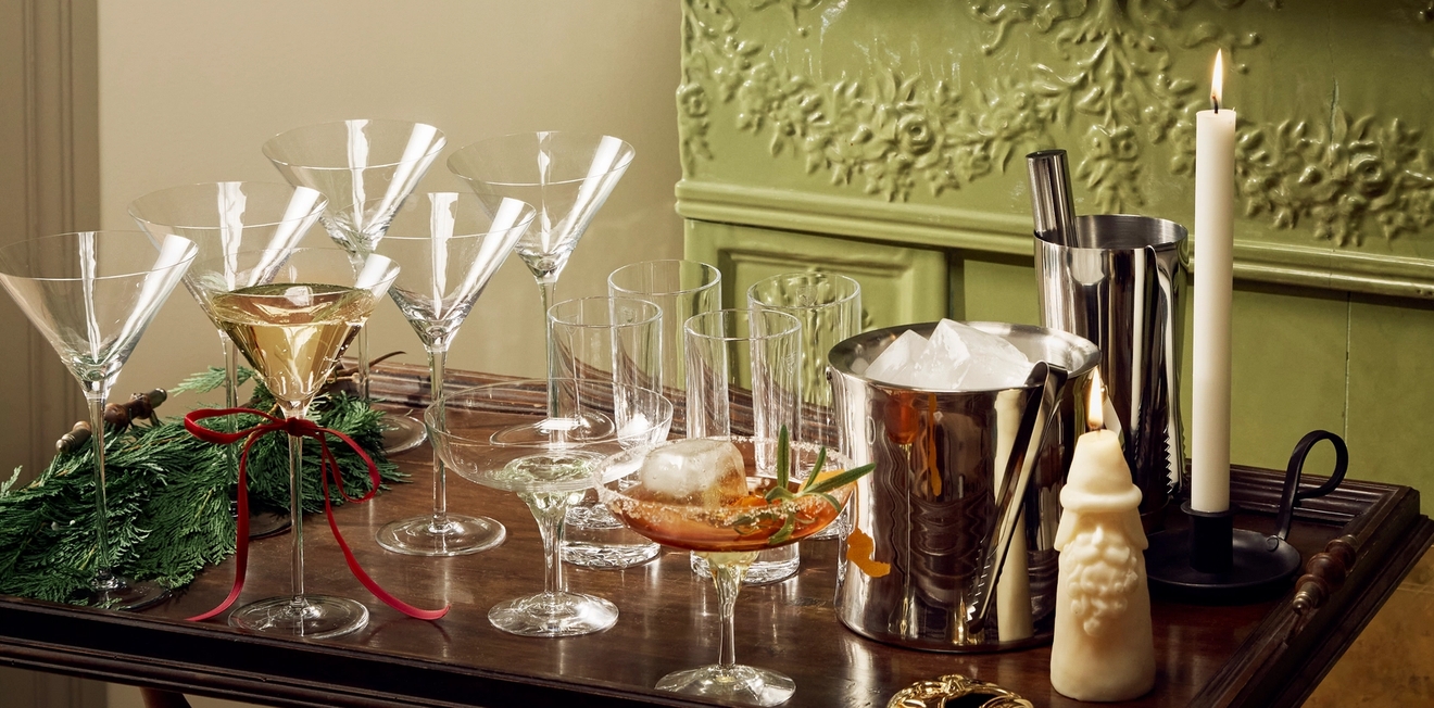 Juomakärry martinilaseineen, jääämpäri ja ravistin seisoo vihreän takan edessä