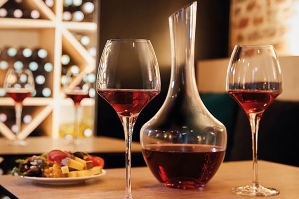 Vinkaraff och två glas med rött vin på ett bord i en stämningsfull vinkällare.