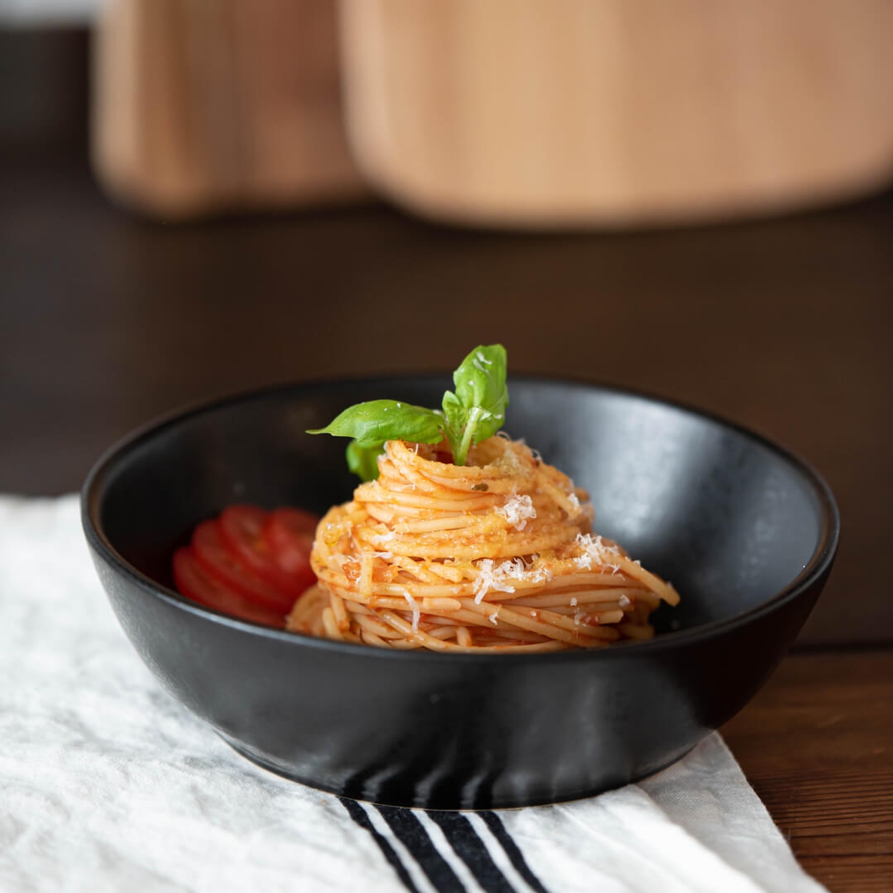 Pastatallrik i svart med spagetti och tomatsås toppat med parmesan och basilika 