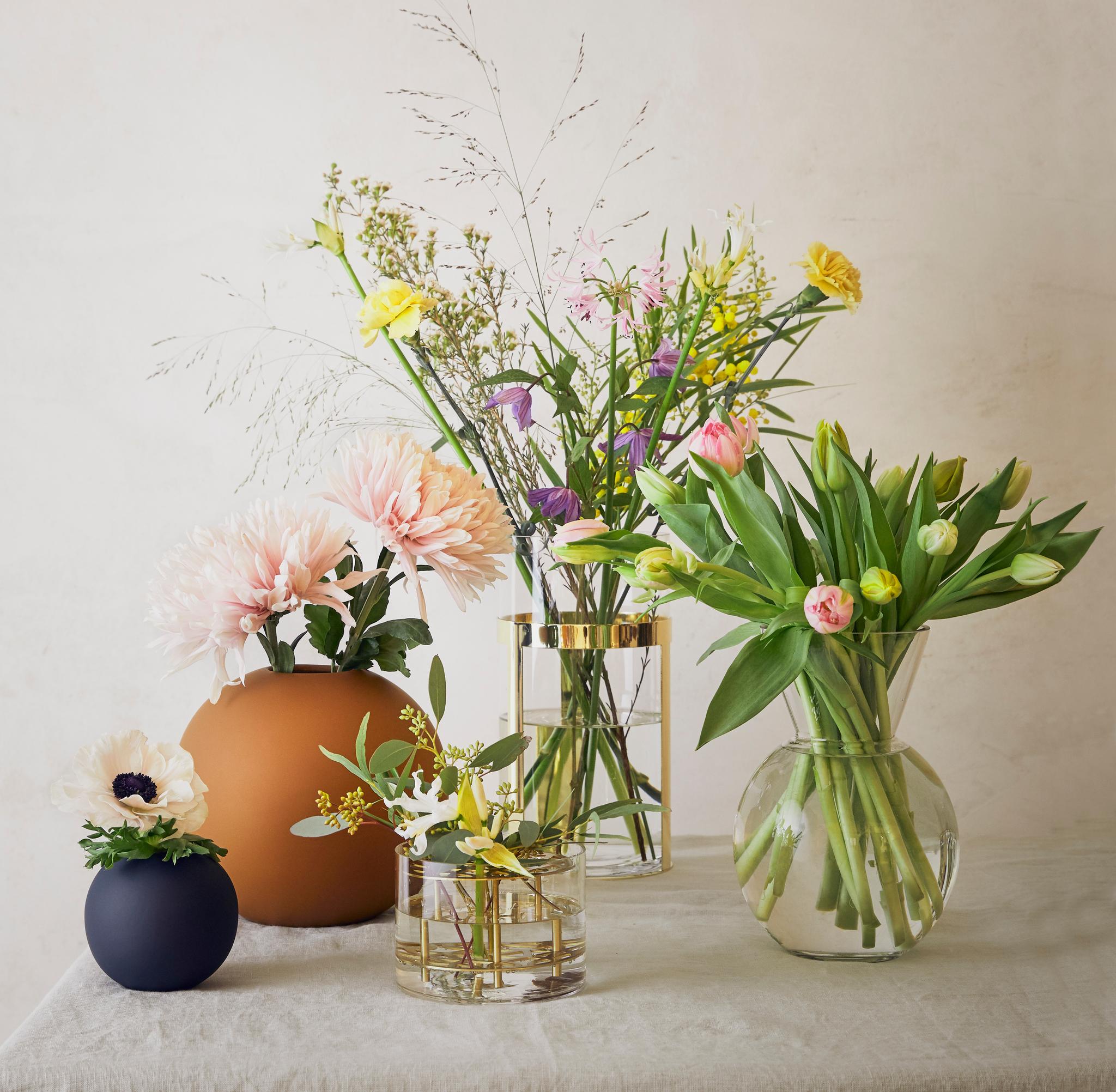 Pyöreät cooee maljakot ja sylinterin muotoiset lasimaljakot kultaisilla yksityiskohdilla kukkakimppujen kera