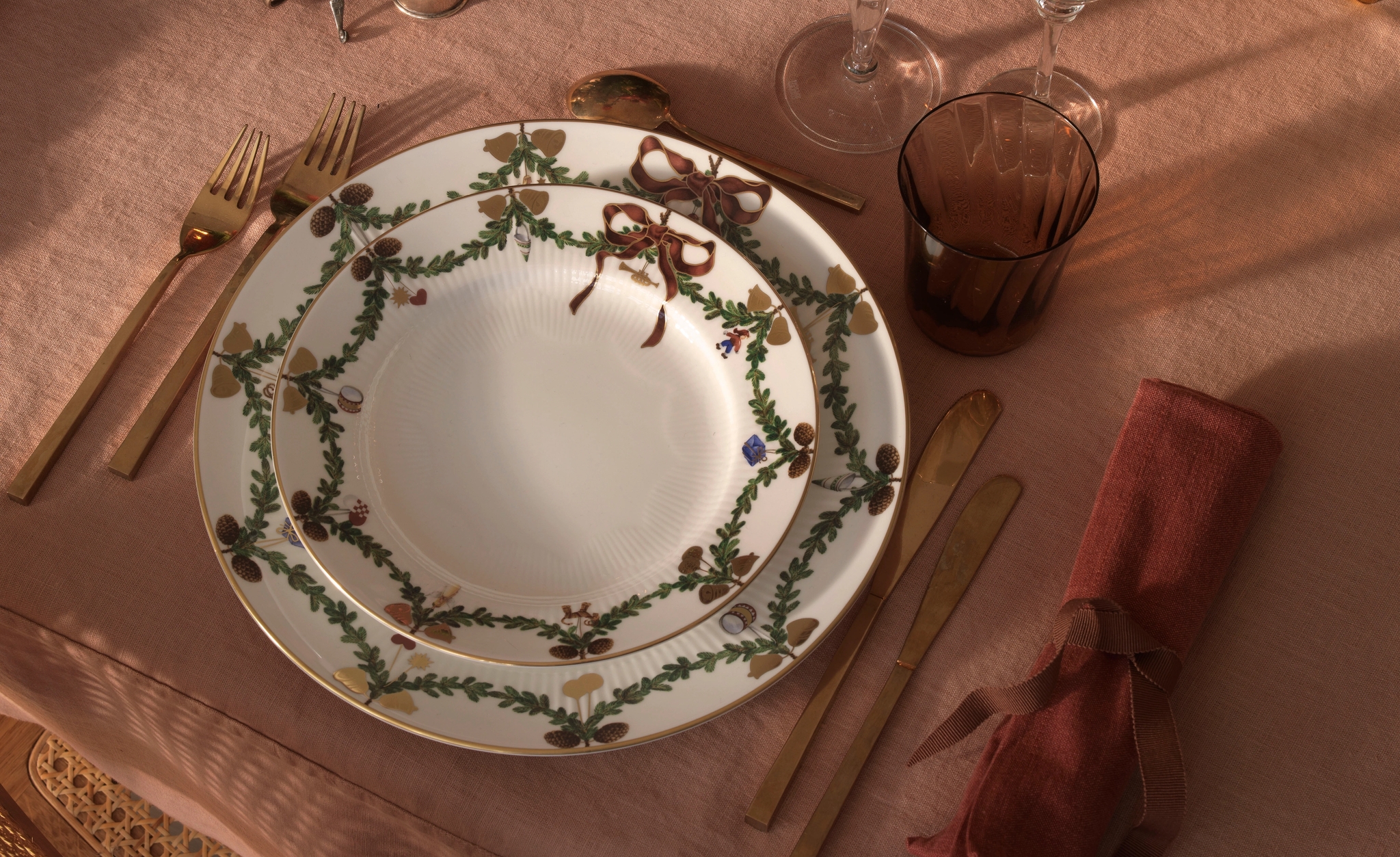 Ett dukat bord för en middagsbjudning med julporslin, ljus och blommor.