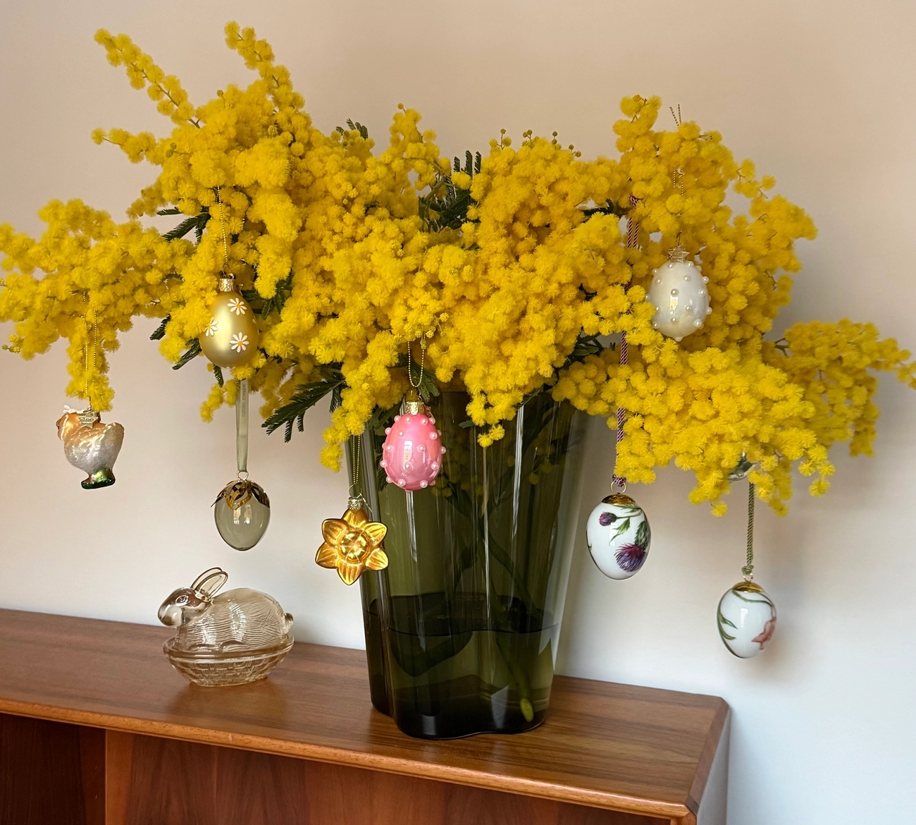 Bright yellow mimosa flowers adorned with various Easter egg ornaments.