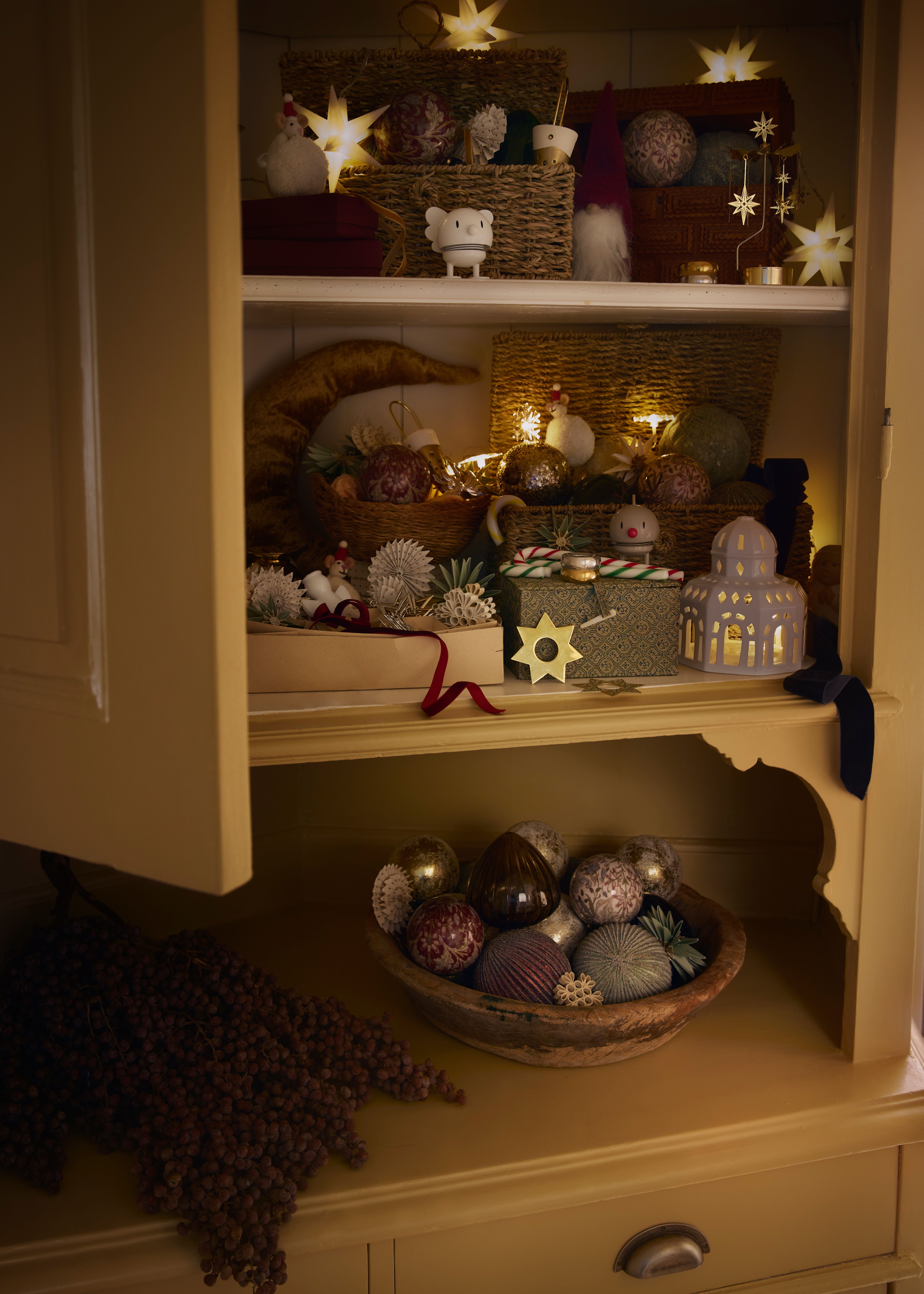 et skap fylt med julepynt og en skål med julekuler