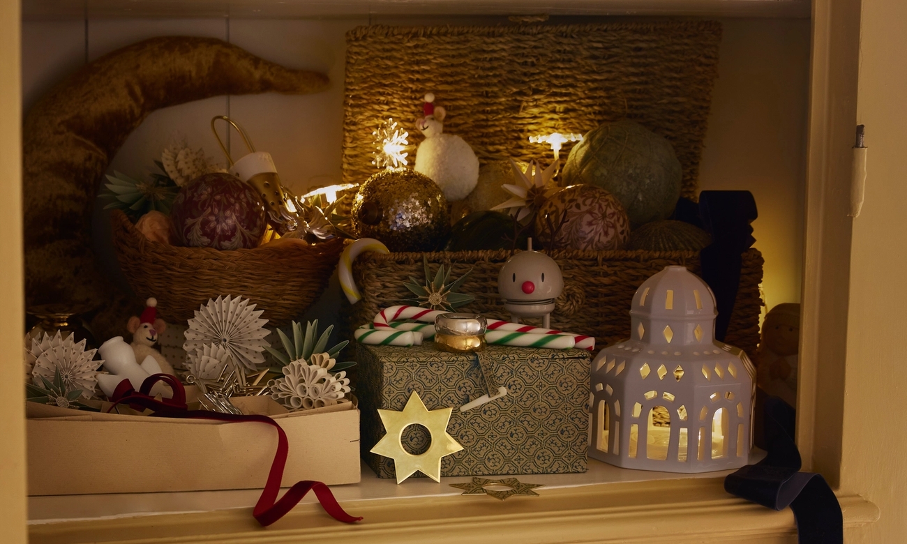 Ett rustikt skåp är dekorerat med varmt glödande stjärnljus, festliga ornament och presenter inför högtiderna.