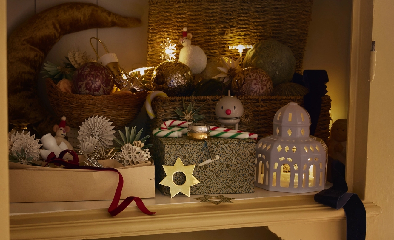 Ett rustikt skåp är dekorerat med varmt glödande stjärnljus, festliga ornament och presenter inför högtiderna.