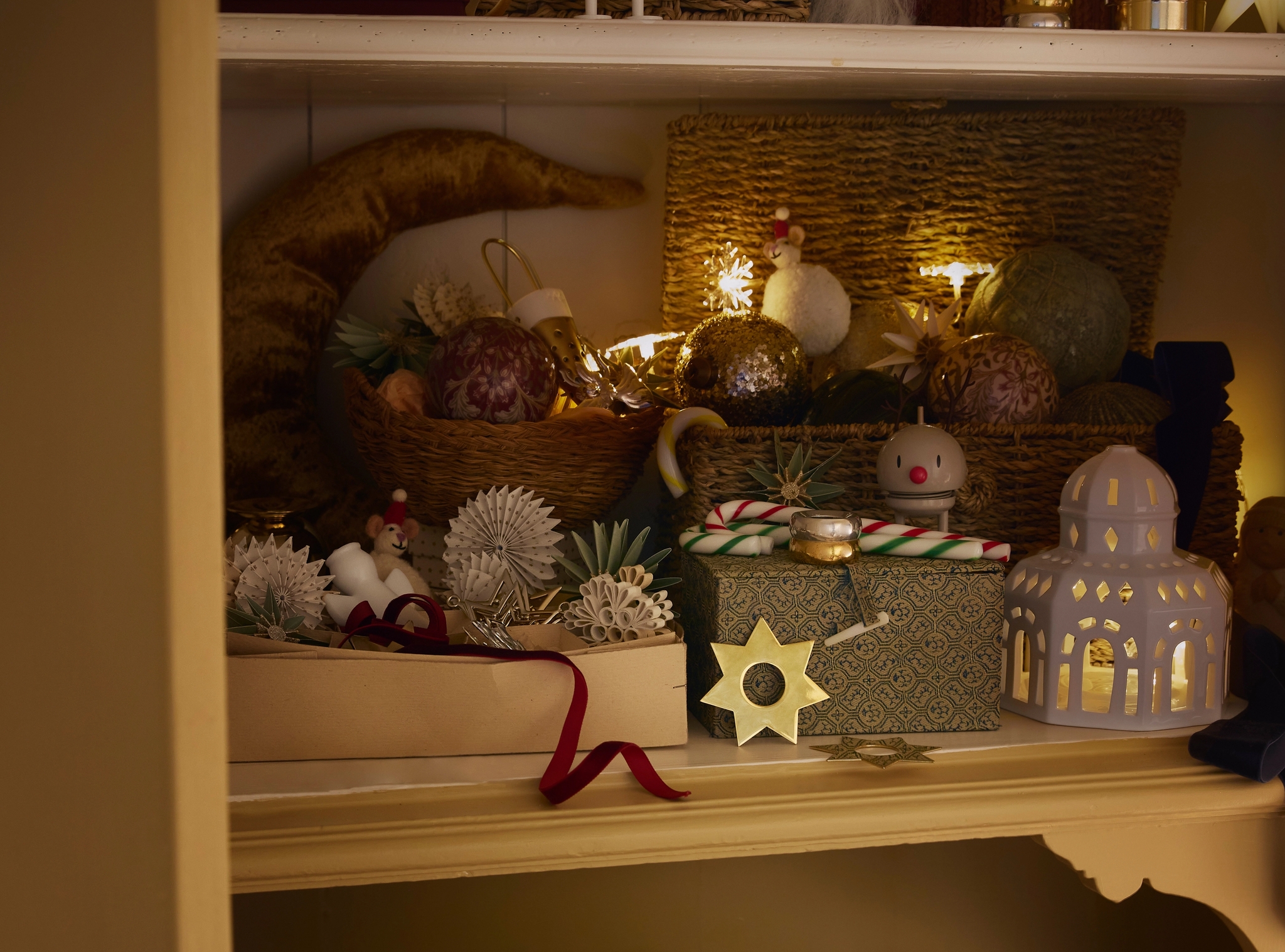 Et skap fylt med juledekorasjoner og en skål med julekuler