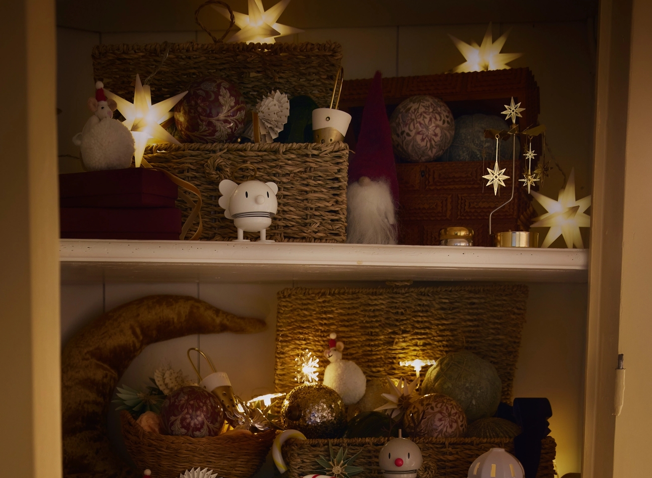 Kotoisa kaappi, joka on koristeltu joulua varten tähtivaloilla, koristeilla, lahjoilla ja hohtavilla valosarjoilla.