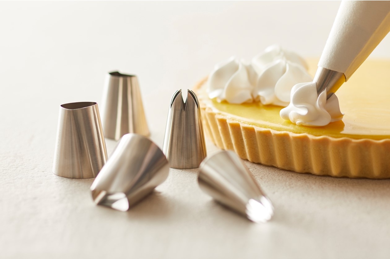 Spritsar som spritsar maräng på lemon curd paj