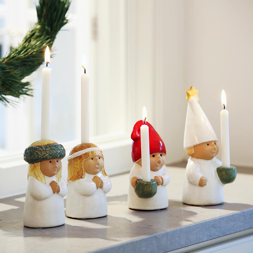 Four ceramic Scandinavian-style figures, including gnomes and a Lucia character, holding lit candles.