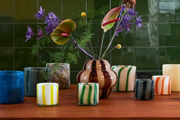 Erikokoiset ja eriväriset ByOn kynttilälyhdyt sekä maljakko puisella pöydällä