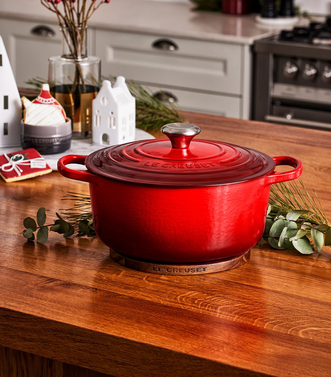 En röd Le Creuset-gryta står på en träbänk