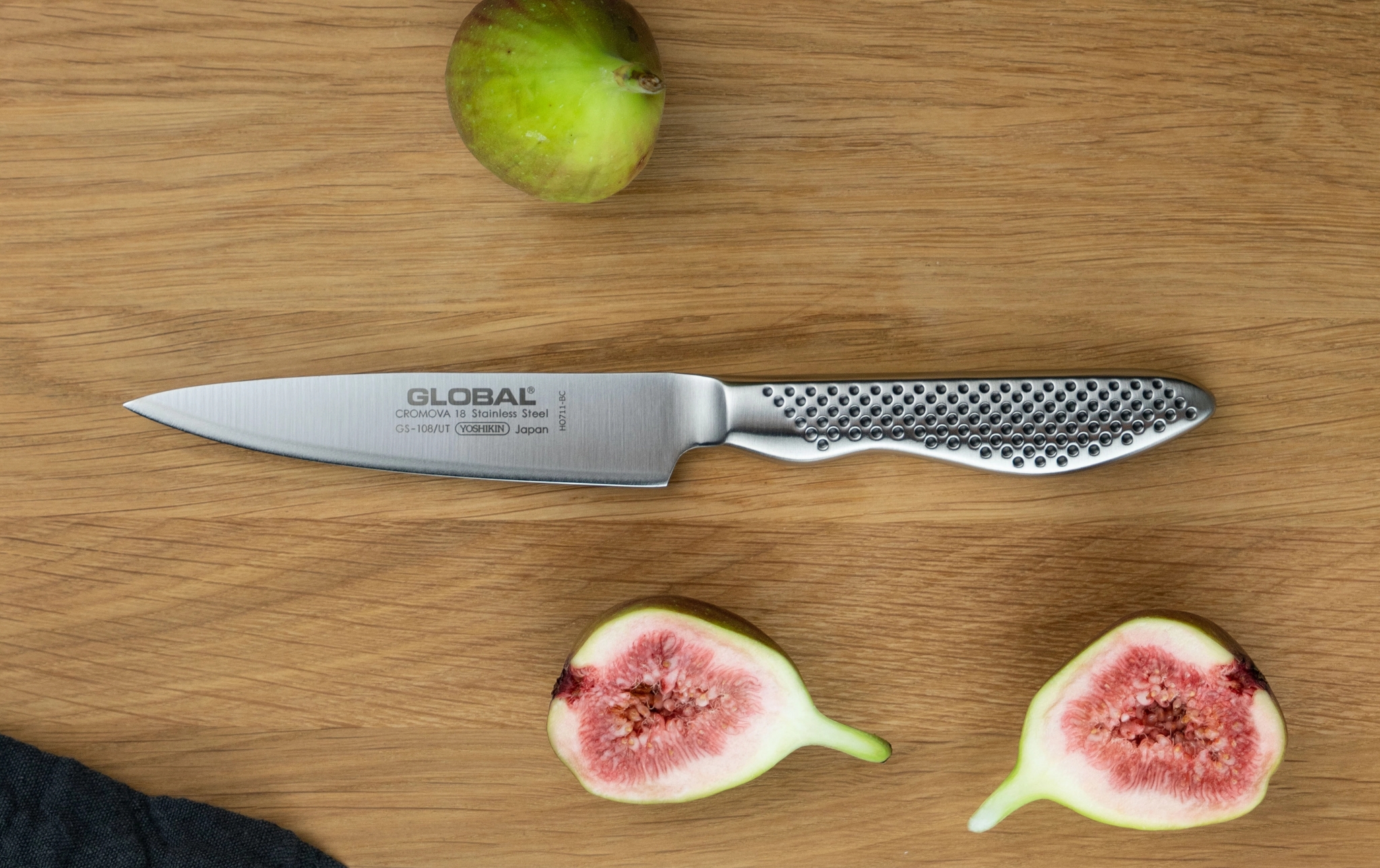 Global-kockkniv på träskärbräda med färska fikon på grå köksbänk.