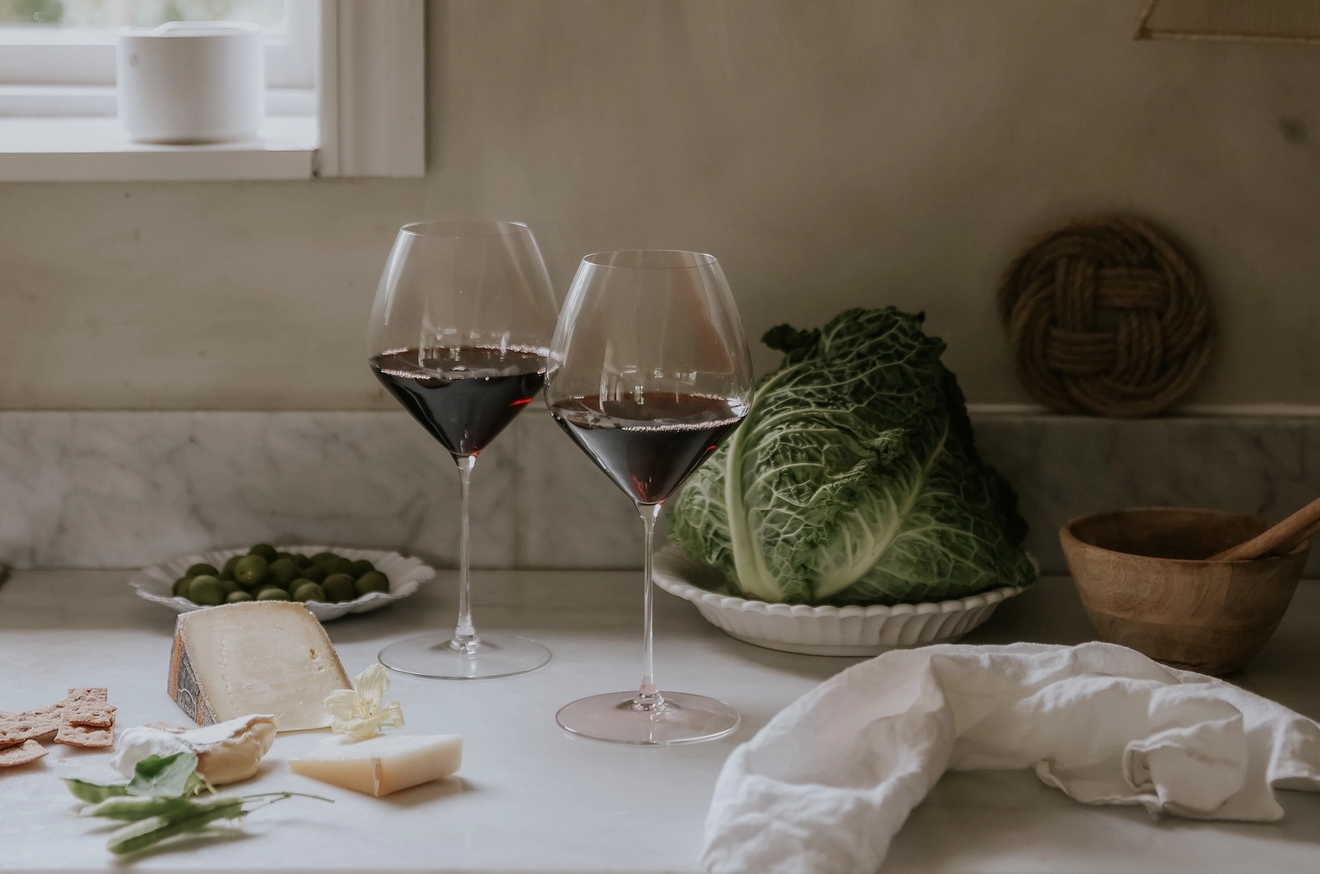 Två glas rödvin står på en köksbänk.