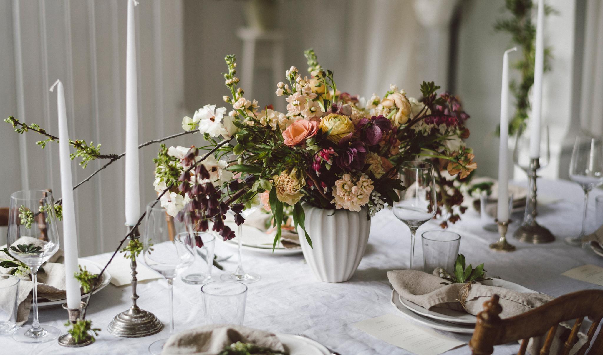 Maffig blombukett i en stor vas på en festligt dukat bord