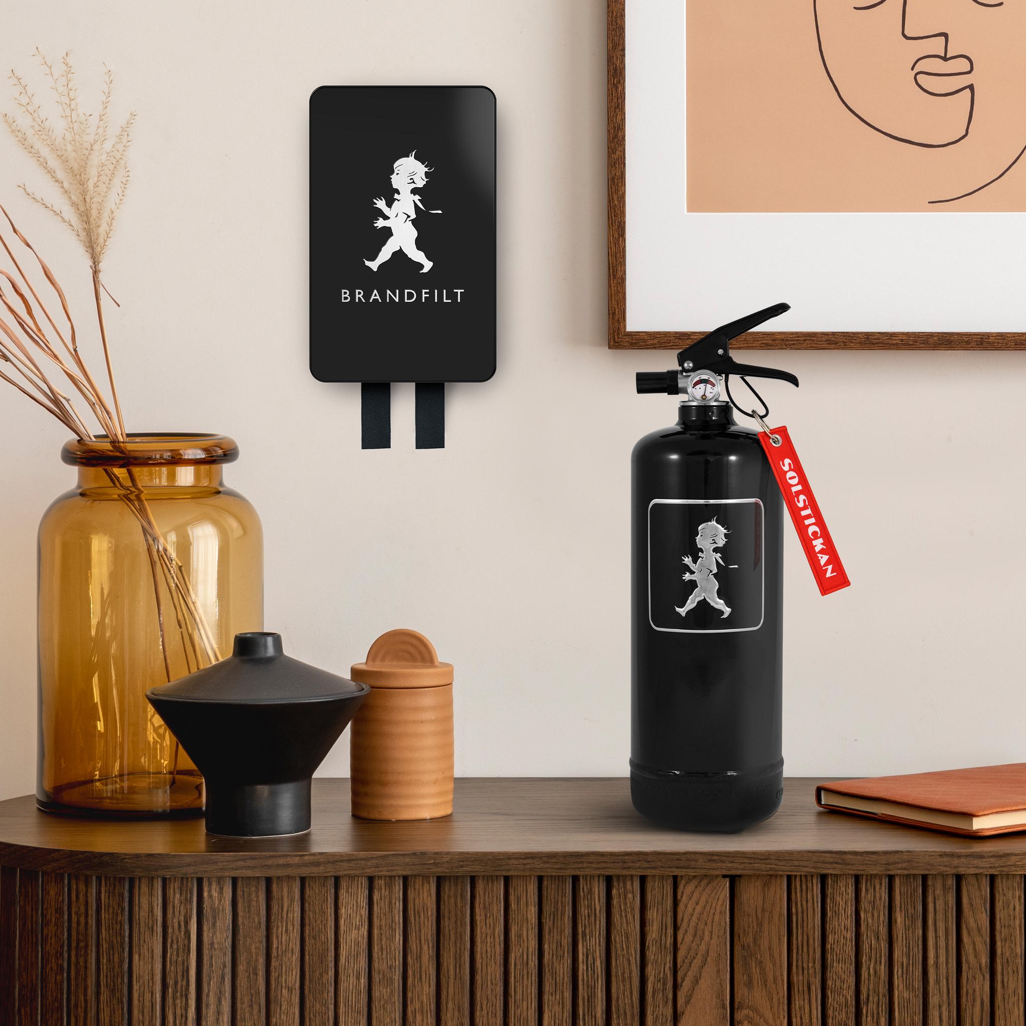 Svart brandsläckare och brandfilt på ett sideboard i trä