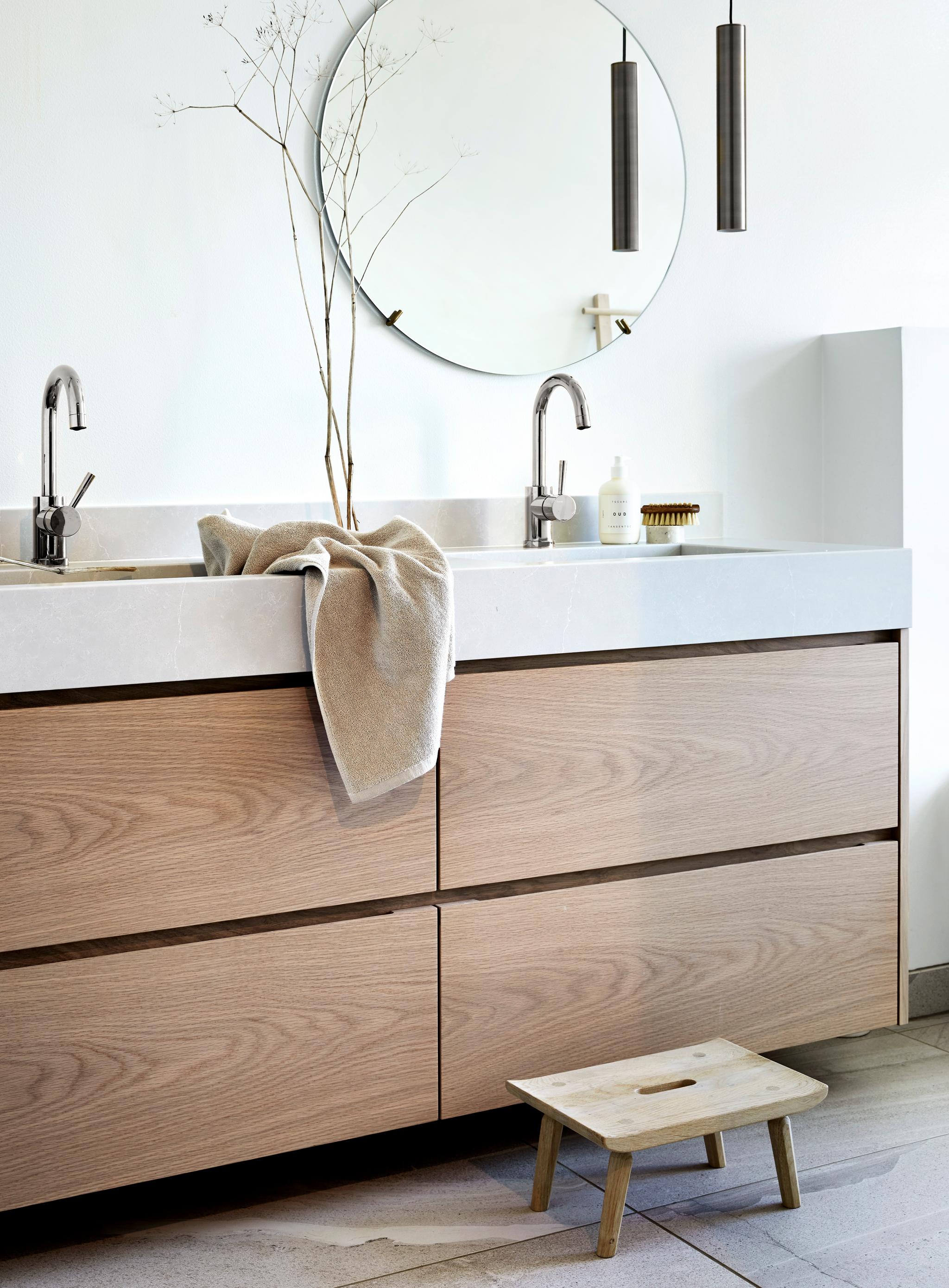 Spegel, handfat och kommod i trä i ett badrum