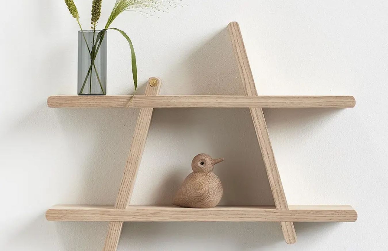 Trä hylla på en vägg med en träfågel och en vas med blommor