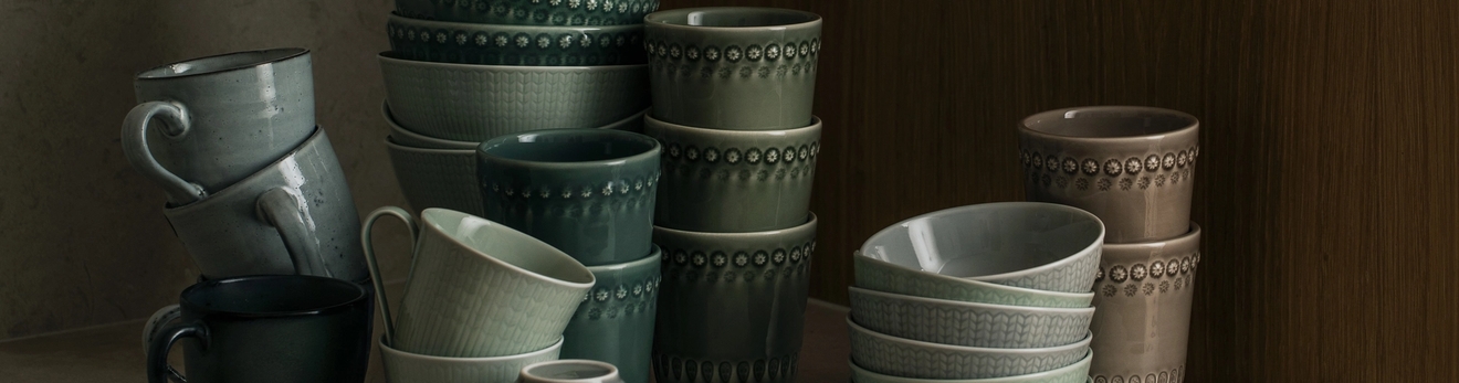 Gröna, grå och bruna koppar som är staplade på varandra