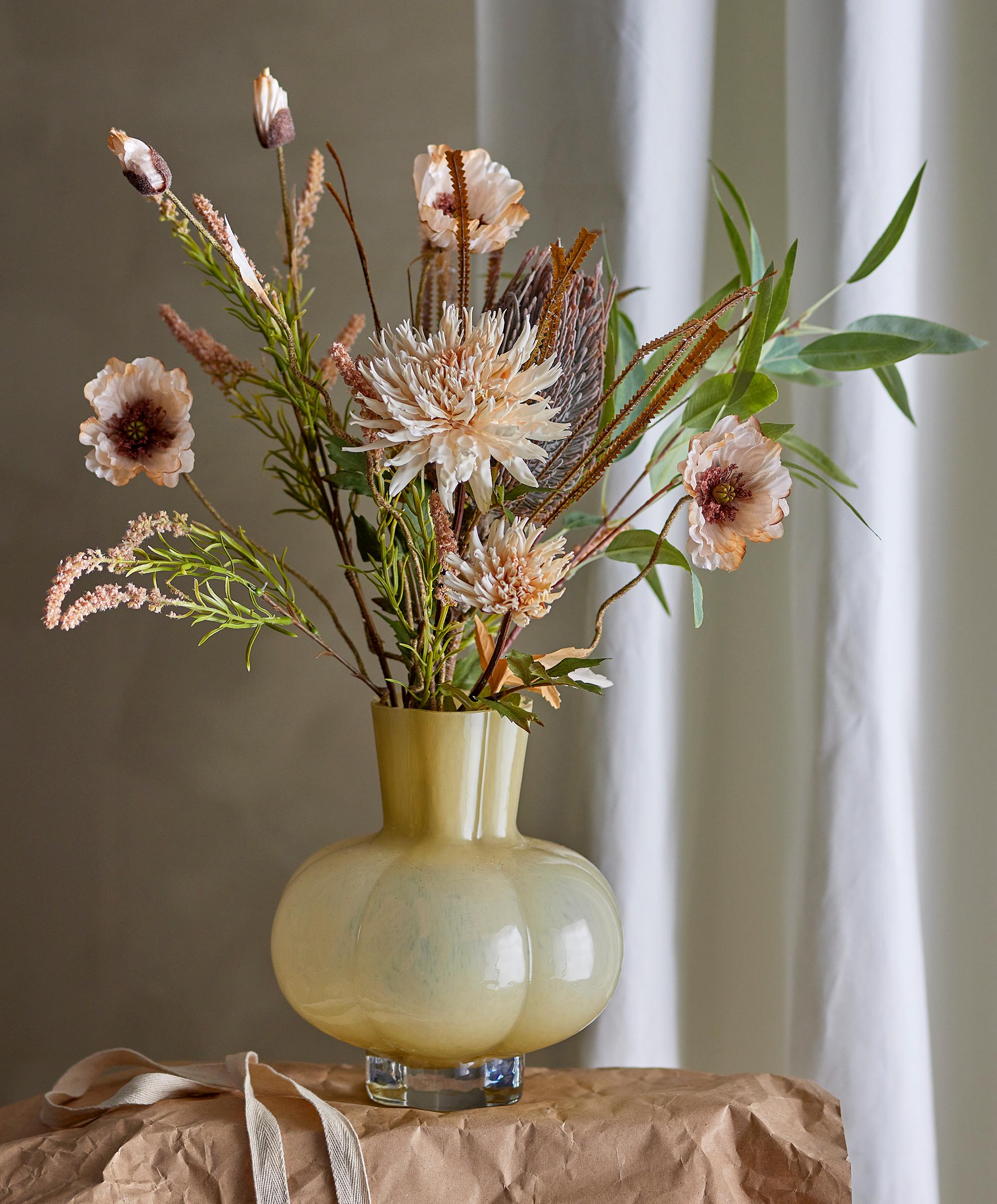 Gul rund vas med en stor bukett med rosa och vita blommer i sig