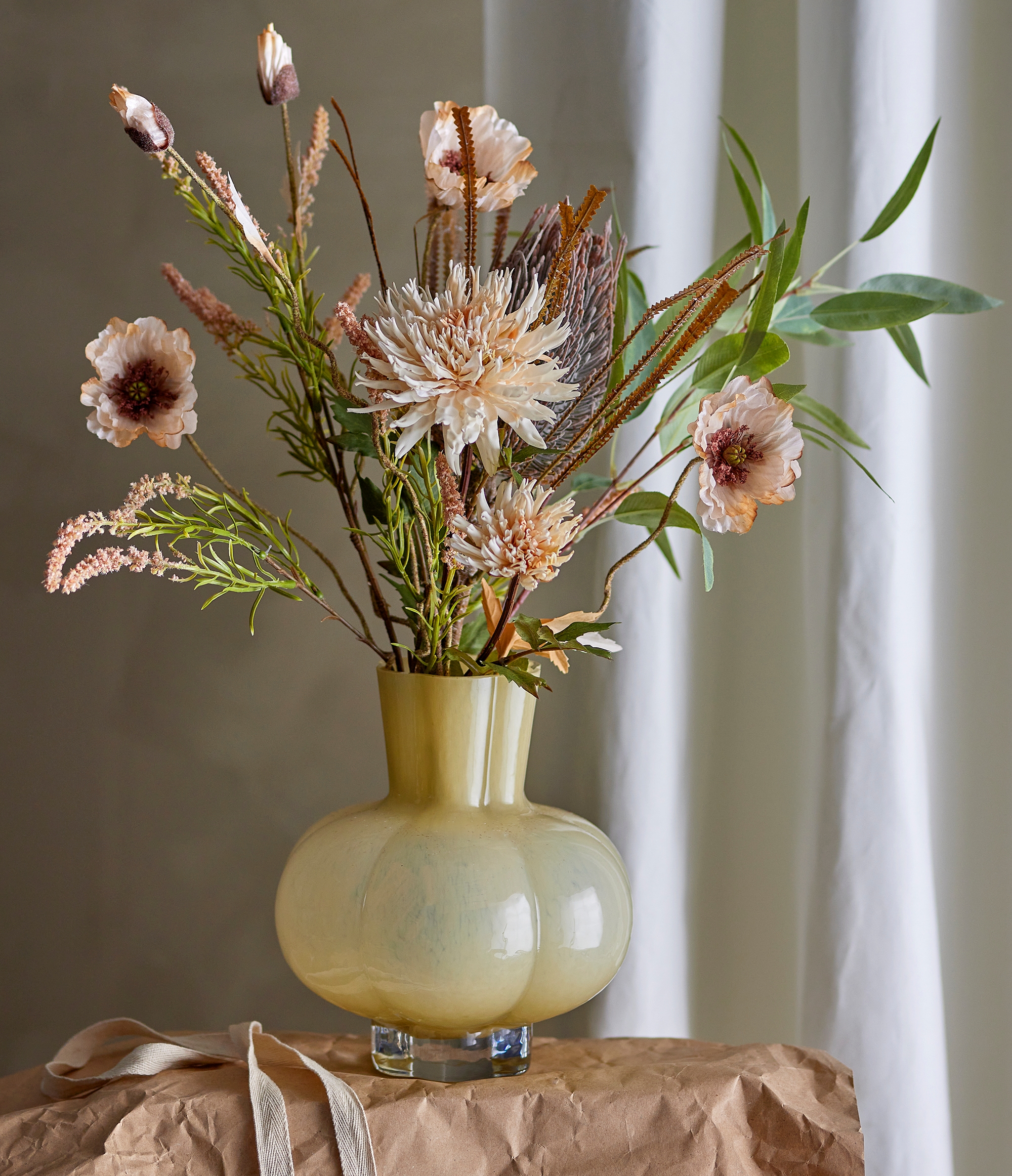 Gul rund vas med en stor bukett med rosa och vita blommer i sig