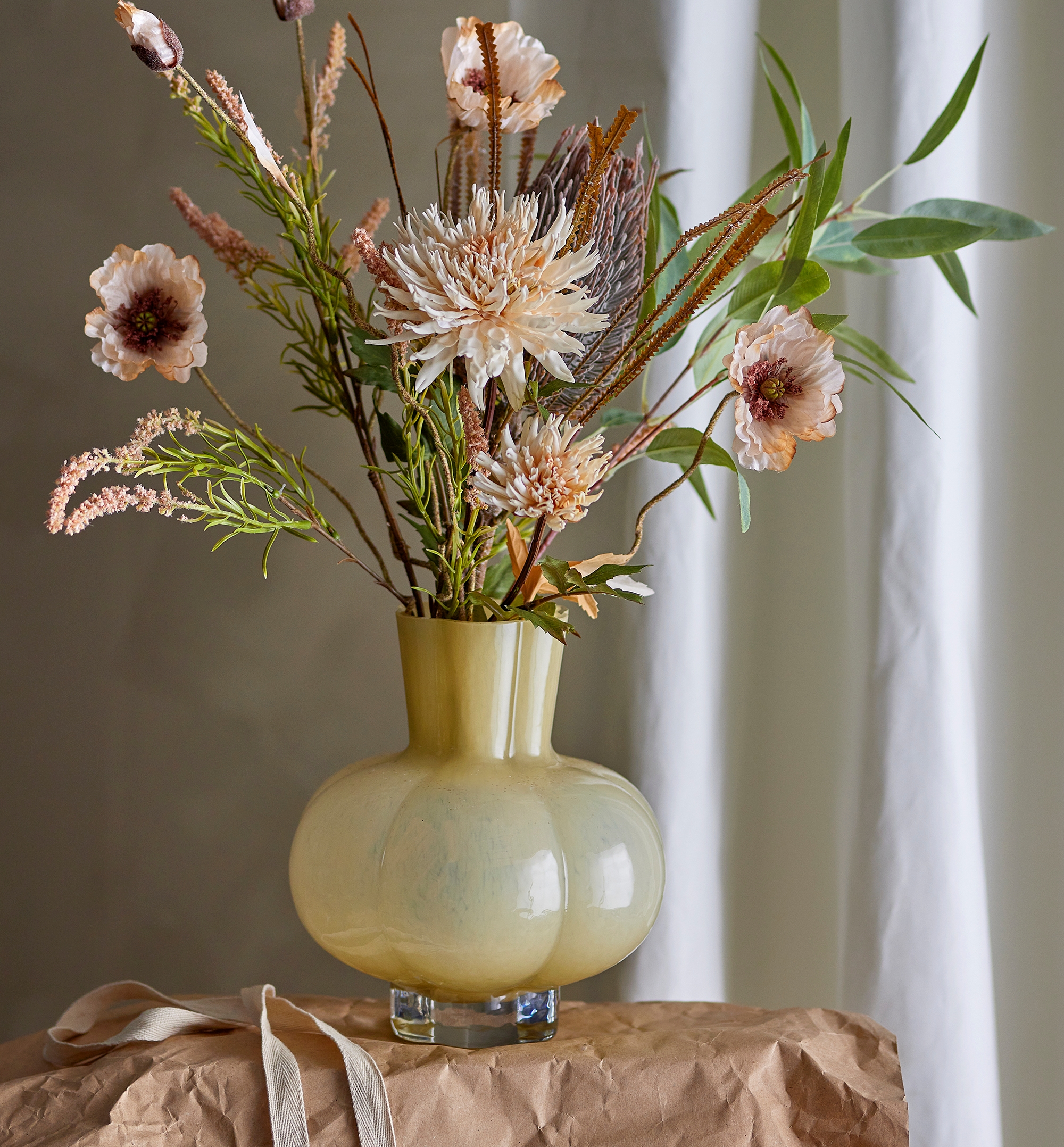 Gul rund vas med en stor bukett med rosa och vita blommer i sig