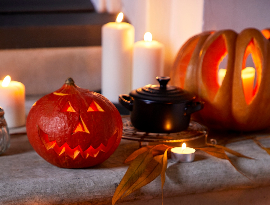Punainen valurautapata, kaiverretut kurpitsalyhdyt ja kynttilät luovat lämpimän halloween-tunnelman.