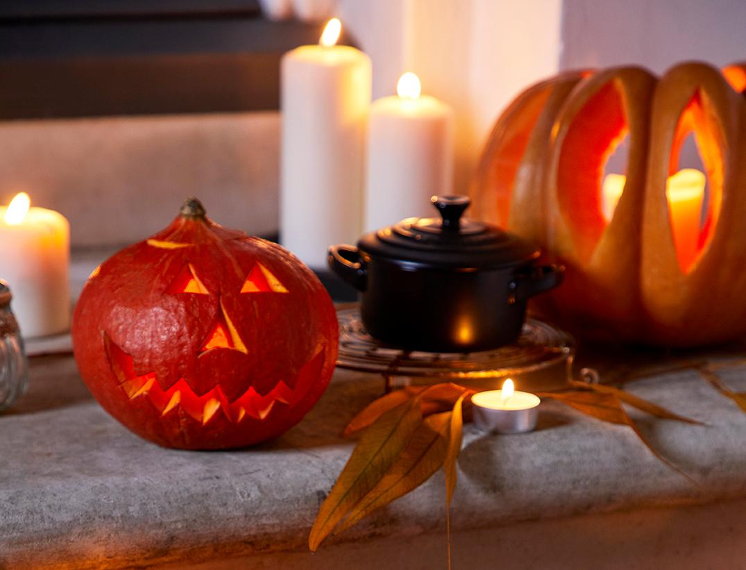Punainen valurautapata, kaiverretut kurpitsalyhdyt ja kynttilät luovat lämpimän halloween-tunnelman.